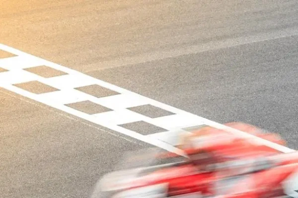Motocicletta sfocata attraversa il traguardo su pista.