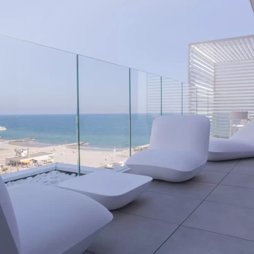 Terrazza moderna con mobili bianchi e vista sul mare.